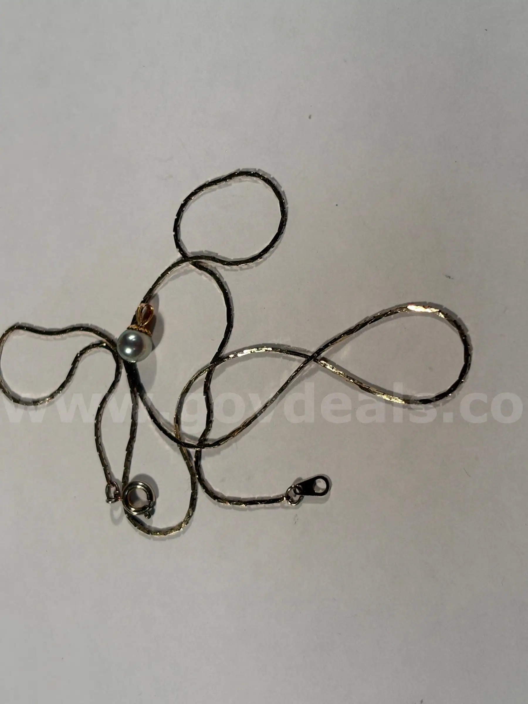 silver colored metal necklace with dark synthetic pearl pendant